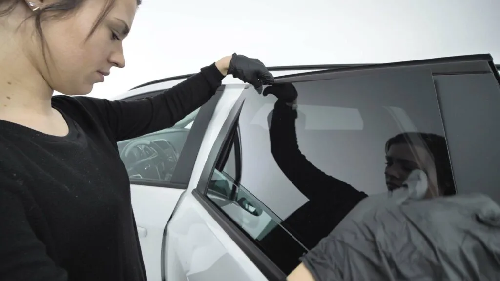 a woman mounts solarplexius pre-cut sun protection on her car window