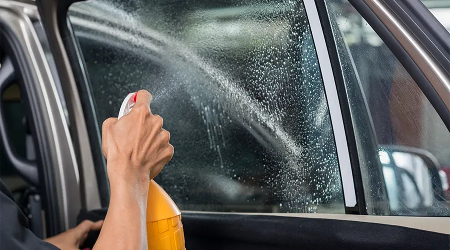 Usando spray limpa vidros para limpar os vidros do carro