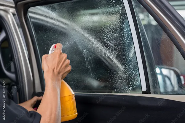 una persona usa uno spray per pulire i vetri dell’auto