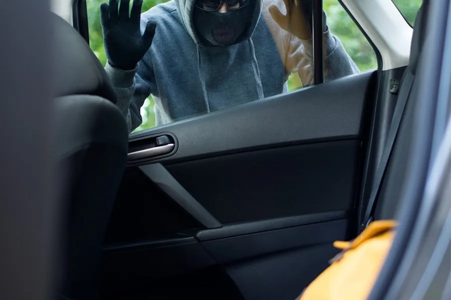 Einbrecher schaut sich die Wertsachen in einem Auto an