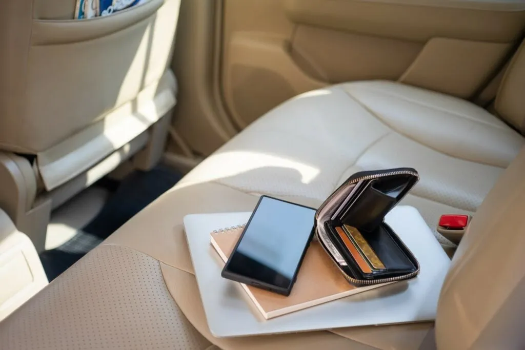 Gennem ruden ses værdigenstande såsom mobiltelefon, pung, dankort og computer eller notebook på et cremefarvet bagsæde. Nedrullede vinduer i bilen er en åben invitation for tyve om at komme indenfor.