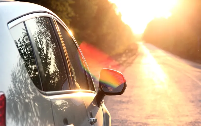 Ein Auto fährt auf einer Straße Richtung Sonnenuntergang